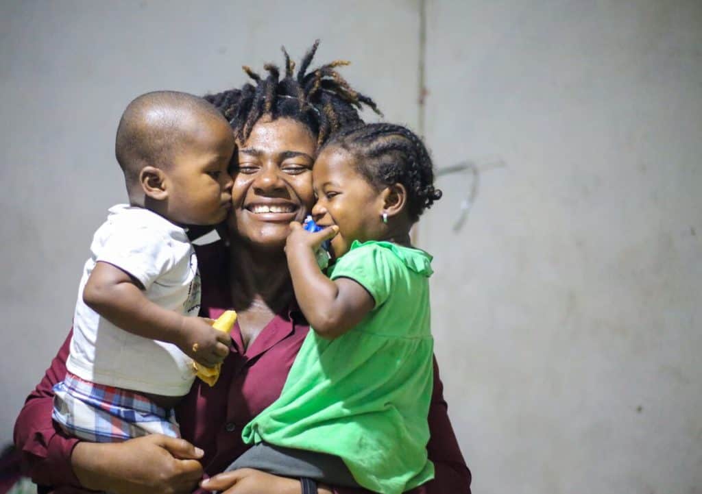 Fabiola is a strong mother in Haiti who is seen smiling and holding her twin toddlers.