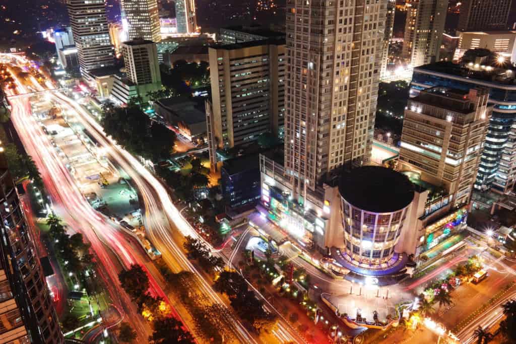 Nighttime in Jakarta. The buildings are lit up and the streets have streaks of lights from vehicles.
