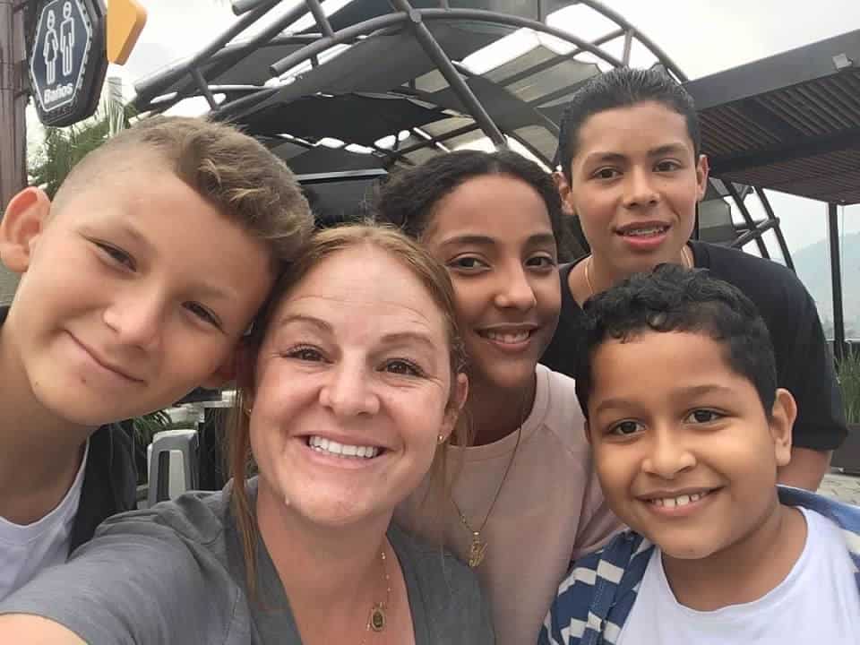 A woman and four children are smiling for the camera. 