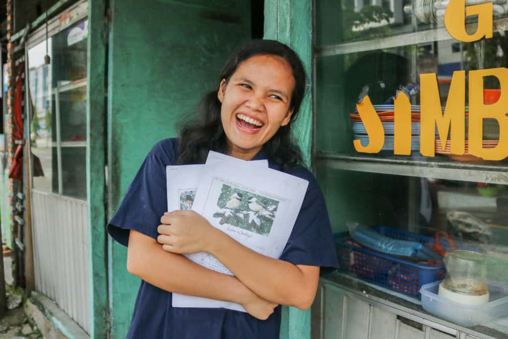 Ani is wearing a navy blue shirt. She is holding letters from her sponsors in her arms.