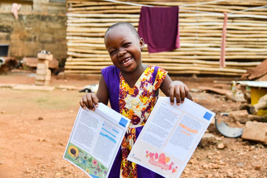 Fortune holds up letters from her sponsors. She is smiling and wearing a colorful dress.