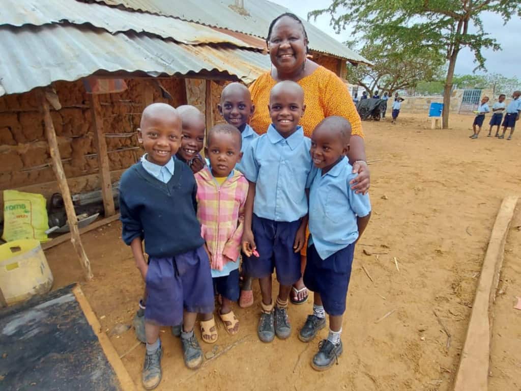 Susan is posing outside with a group of children.