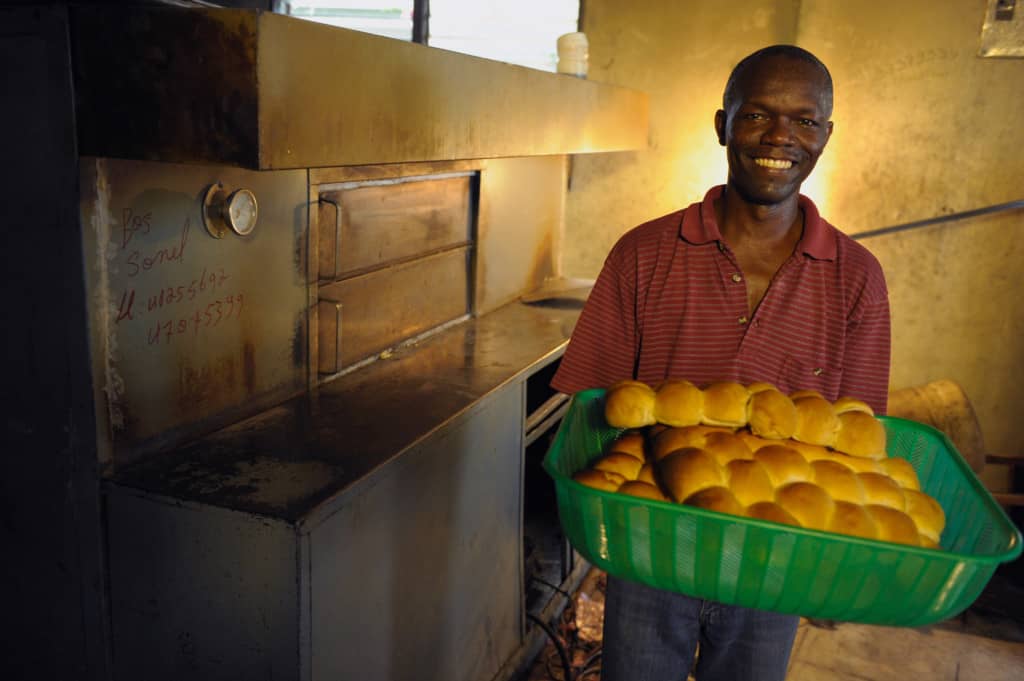 Eriner in his bakery in Haiti holding freshly baked rolls