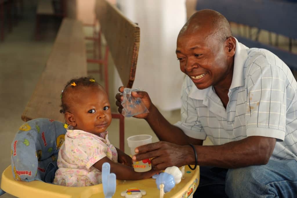 Sylvio feeds his baby daughter a vitamin drink