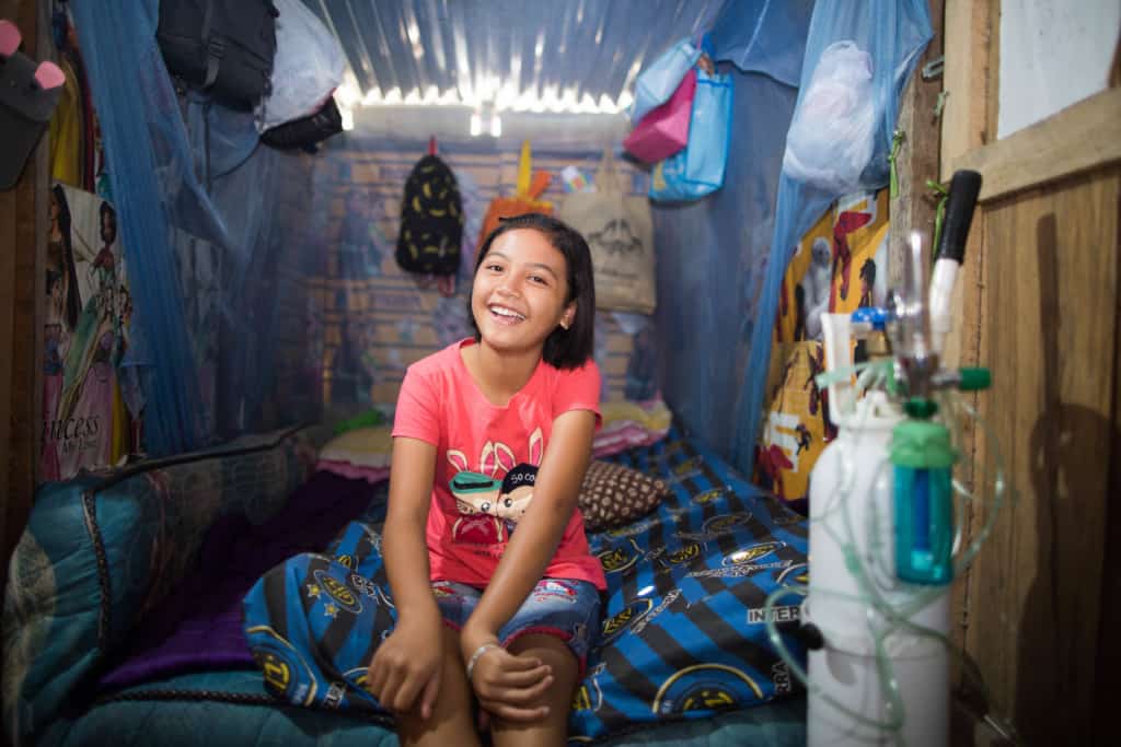 A girl living in poverty with disabilities, sits on her bedroom in her home in Indonesia