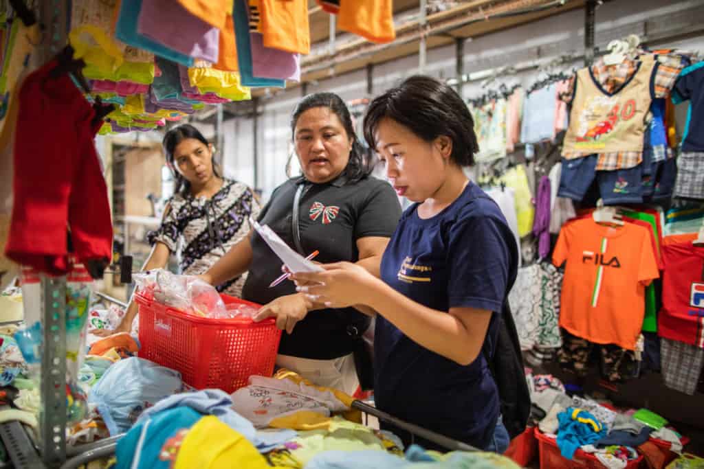 Injilia Mundung (right) is checking a shopping list to make sure 15 Survival beneficiaries get appropriate Christmas gifts. Injilia and Donna Mangindaan (middle) are shopping at one of the clothes shops in Manado city.