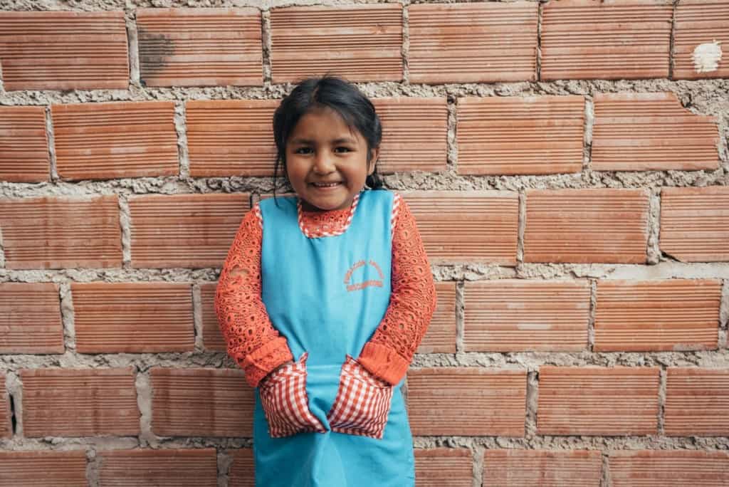 Girl standing in front of a brick wall.