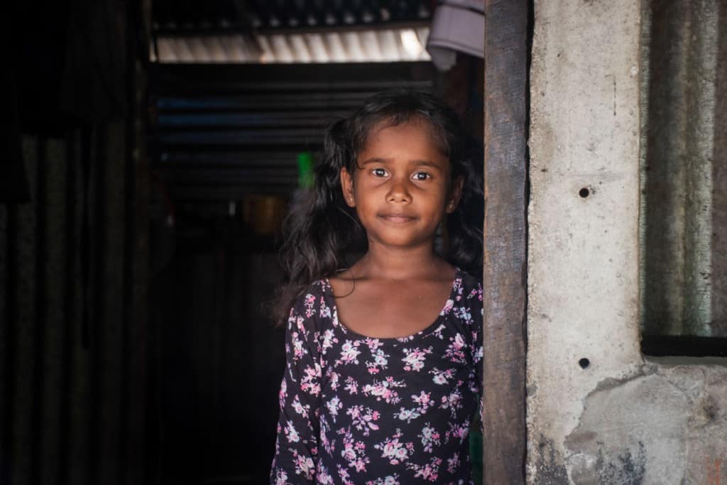 Girl standing in a doorway wearing a dress with a flower print.