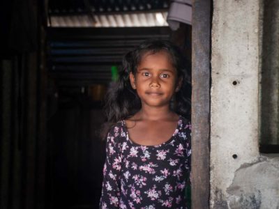 Girl standing in a doorway wearing a dress with a flower print.