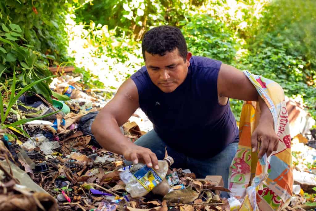 Orlando, wearing a dark blue shirt, is looking for items he can recycle in the local landfills.