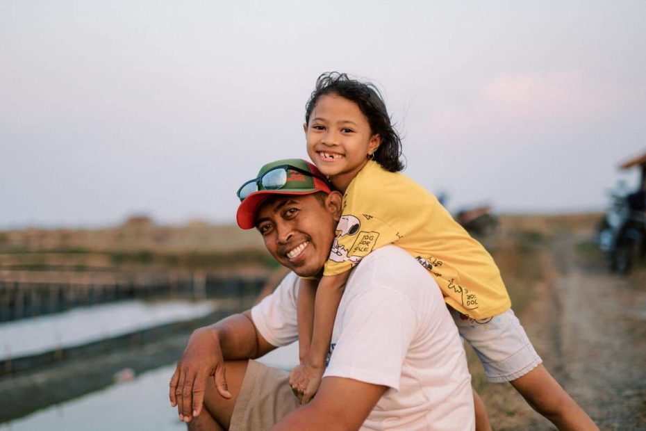 A father and daughter are smiling together.