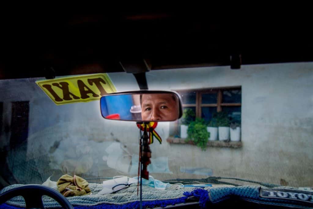 A man looks into the rearview mirror of a taxi in Bolivia.