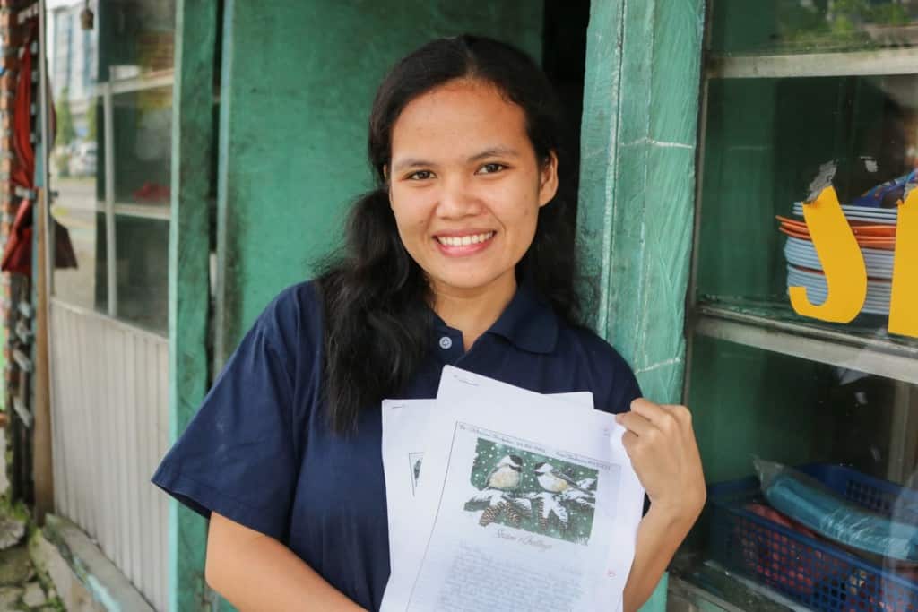 Ani is wearing a navy blue shirt. She is holding letters from her sponsors in her arms.