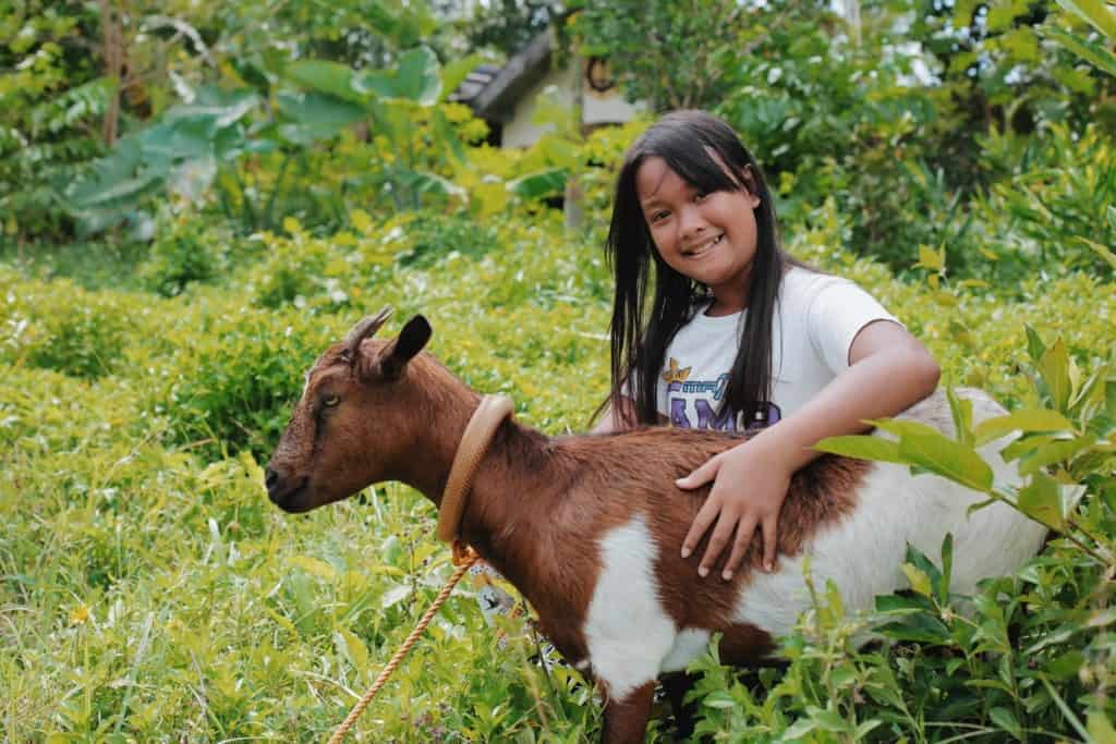 Keasha, in a white shirt, is with her female pet goat "Mee," whose name was derived from the sound it makes.