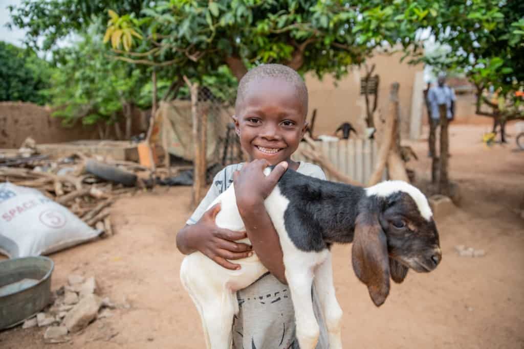 Daniel is wearing a gray shirt. He is holding a lamb, which was a gift from his sponsor.