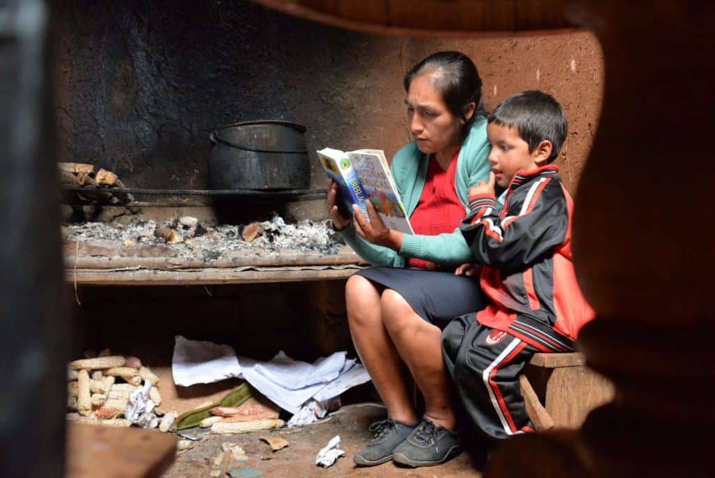 Woman reading to a young boy in a dark room.