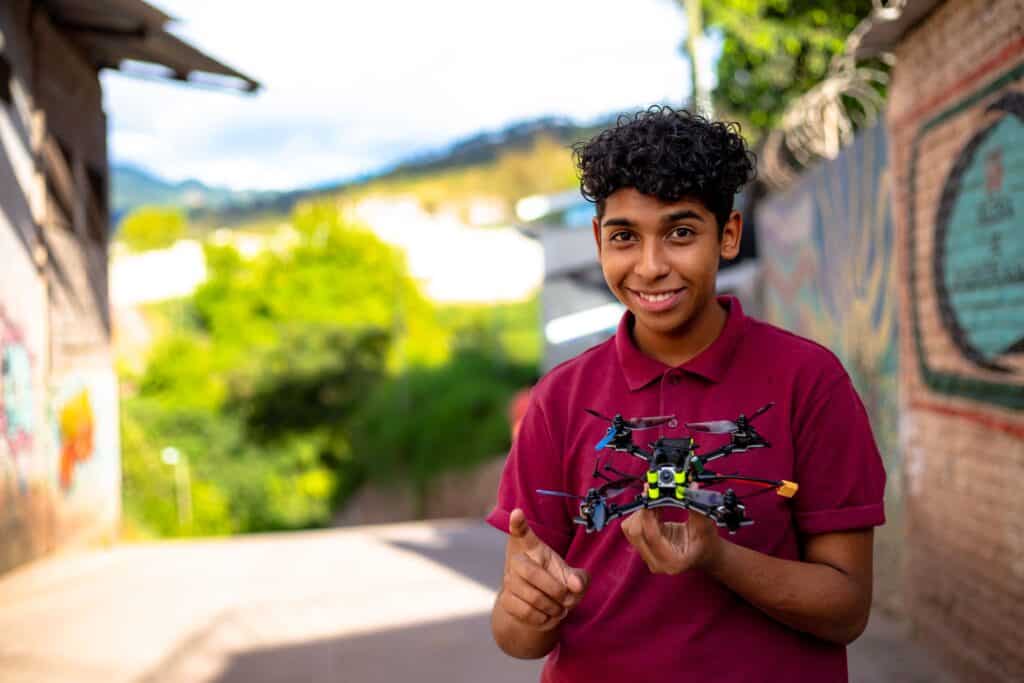 Boy holds a drone and smiles at the camera