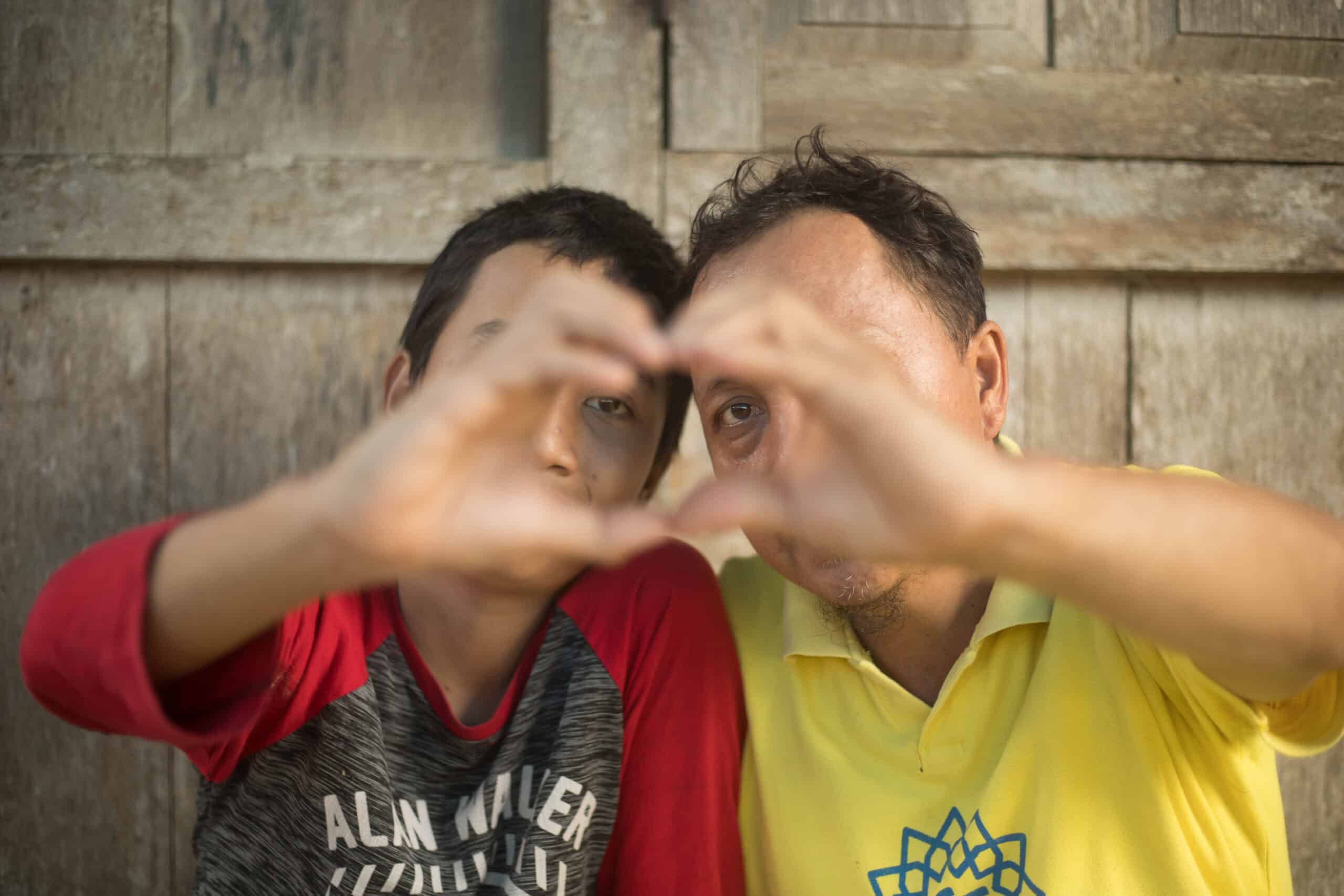 Two boys hold their hands together in the shape of a heart. 