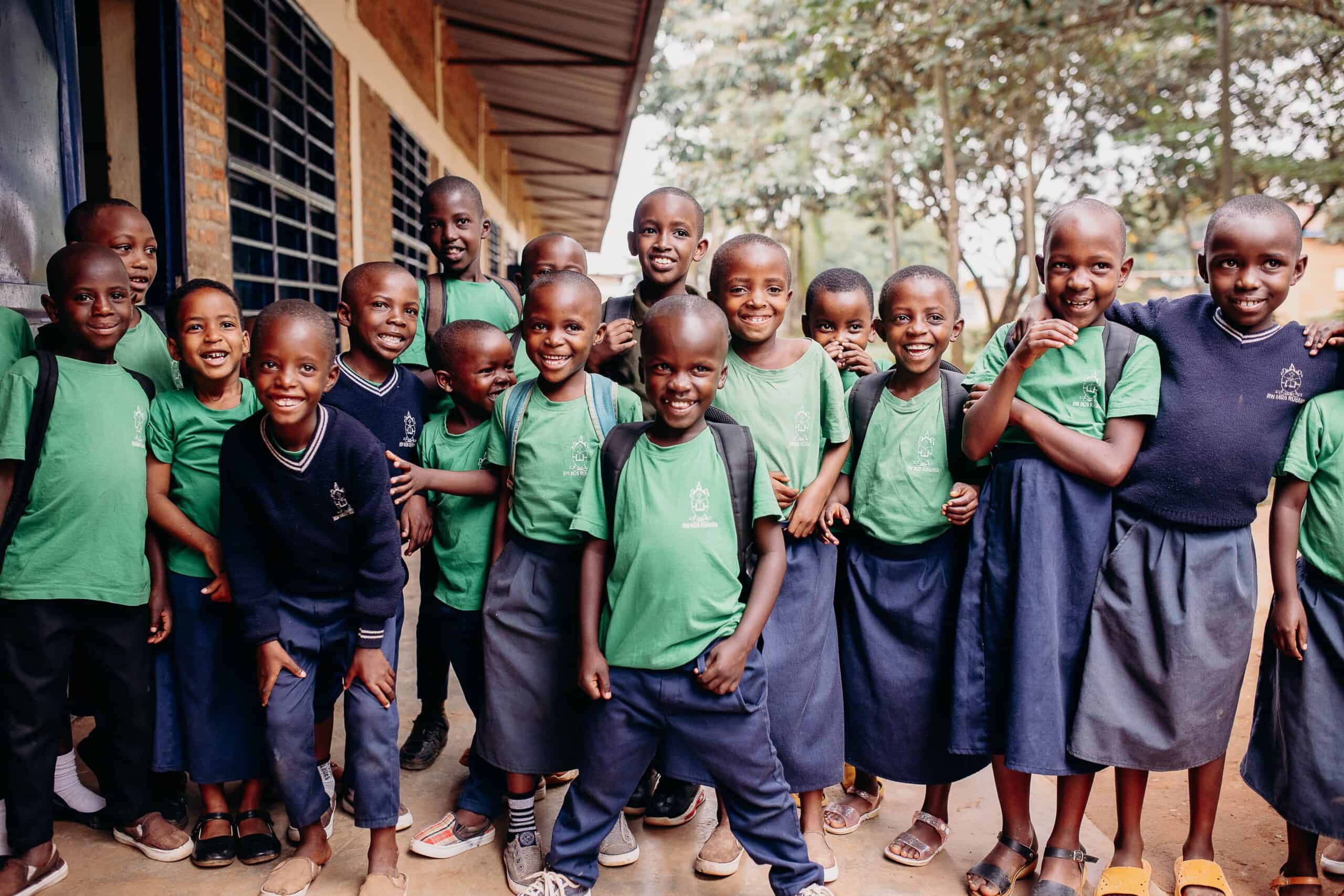 Top 10 Questions About Compassion International Answered. A group of children stand outside of school smiling at the camera.