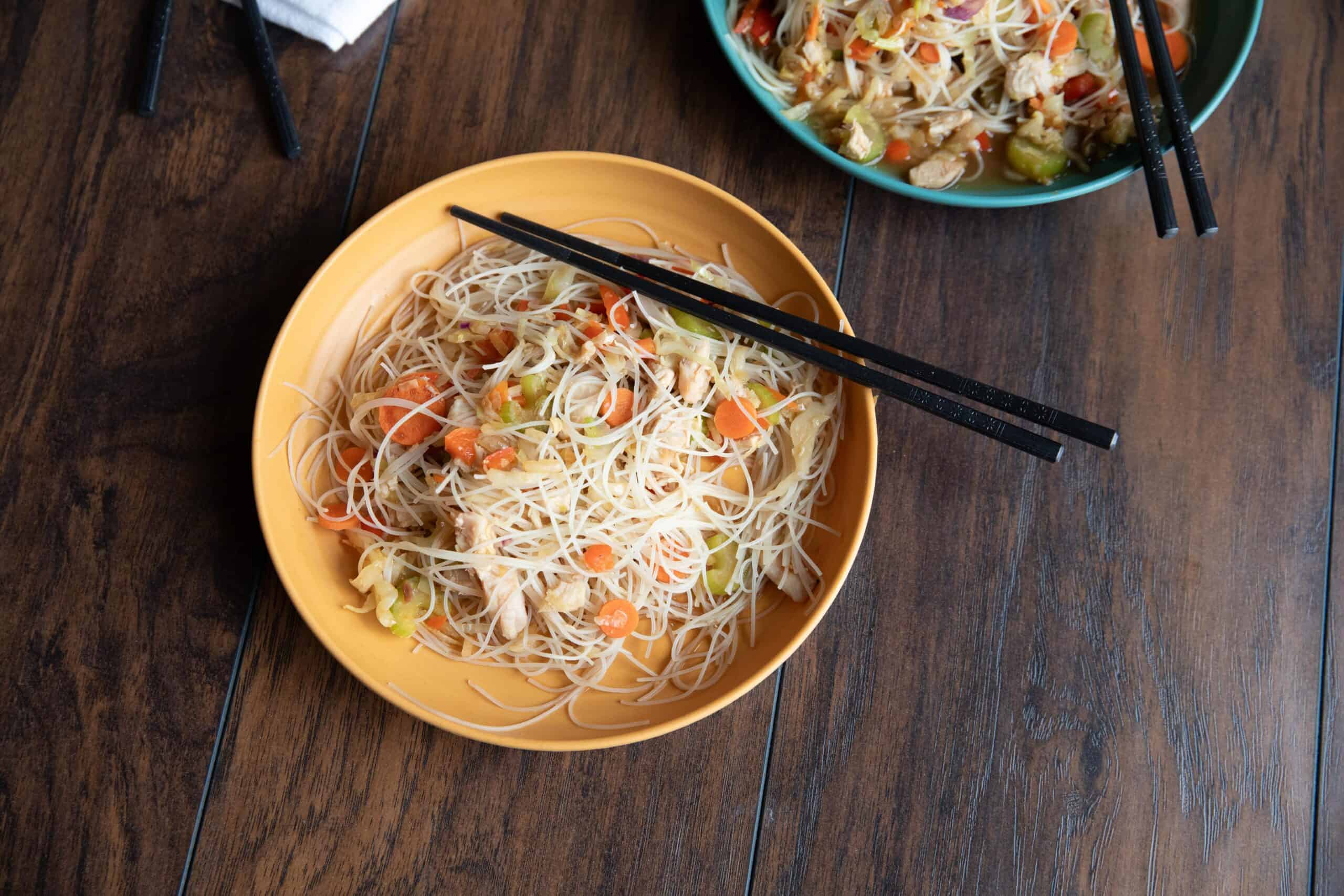 Rose’s panic noodles sit in a yellow and blue bowl underneath a pair of chopsticks.