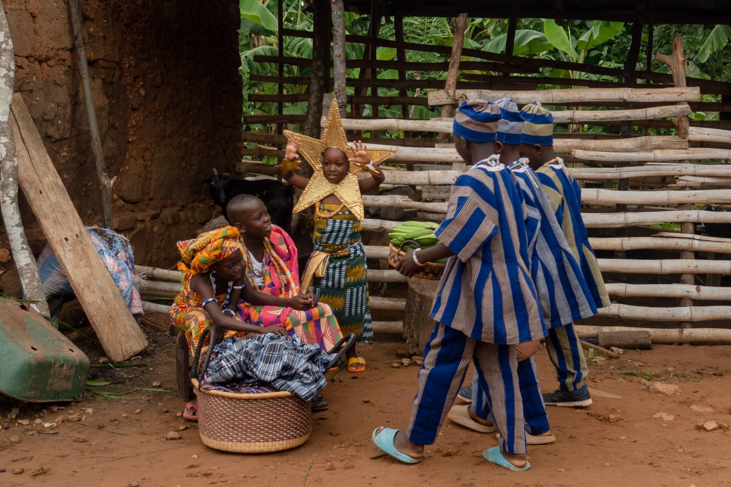 CC-TG0946-Nativity-086-2506-min A group of children dressed as characters from the Nativity Story enact a scene, with a wooden fence in the background.