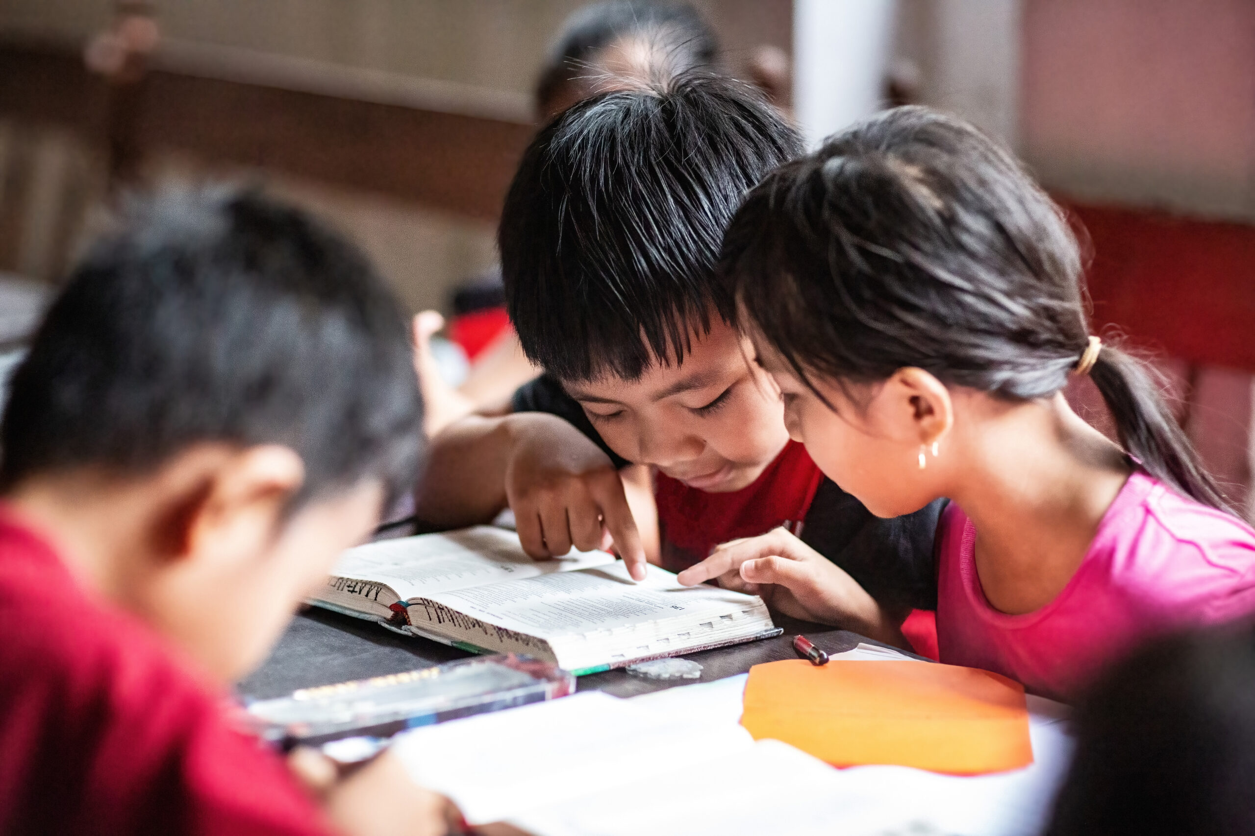 A young boy and girl sit close while reading a Bible at a Compassion center.