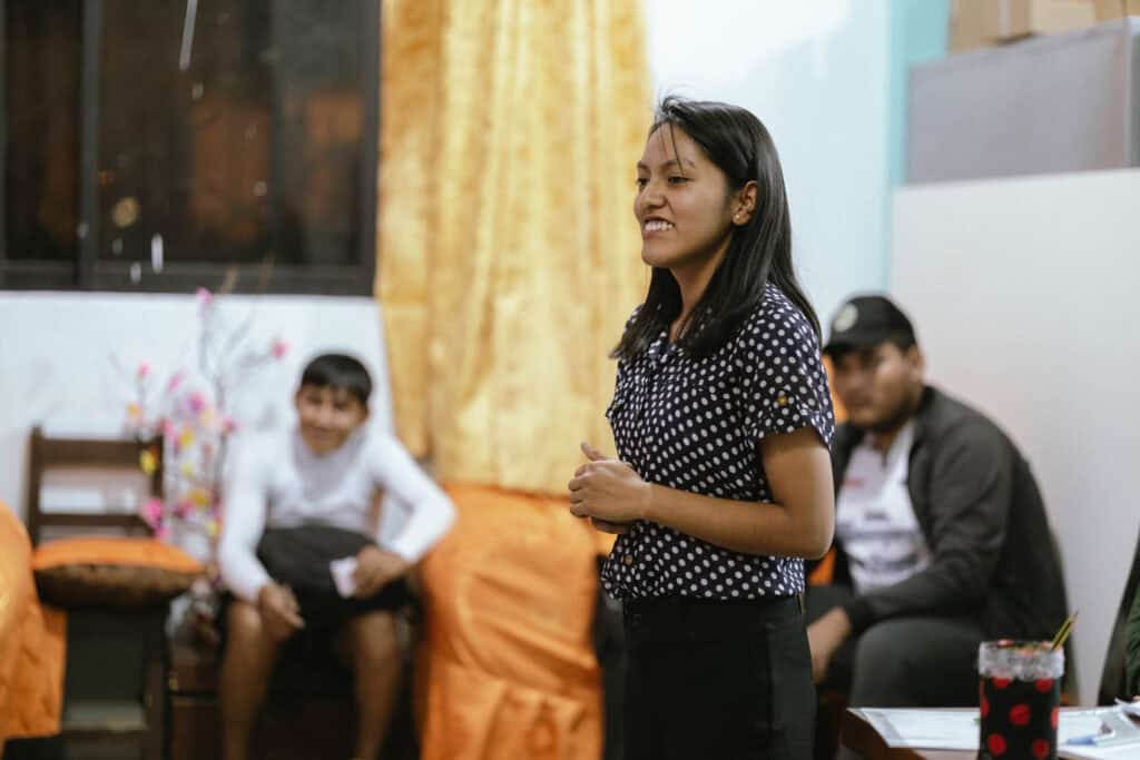 A young woman stands and smiles.