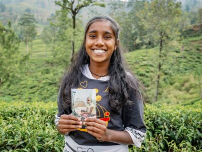 CC-LK-BeforeAfterSet-03-2303-min A teen girl smiles brightly for the camera while holding a photo of her as a child.
