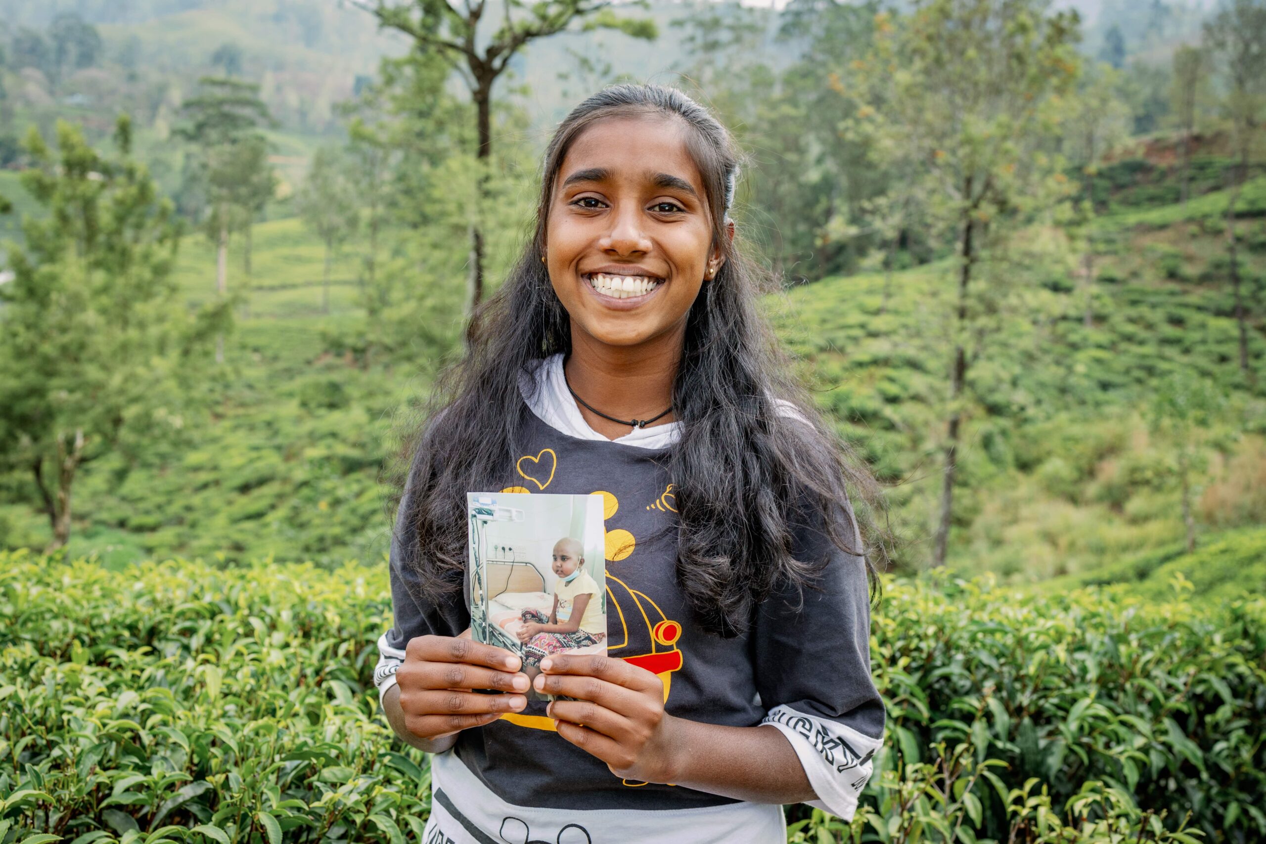 CC-LK-BeforeAfterSet-03-2303-min A teen girl smiles brightly for the camera while holding a photo of her as a child.